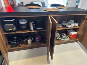 Eine Küche mit einem Holzkasten, einer Kaffeemaschine, einem Wasserkocher und einem roten Kühlbox.