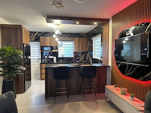A modern kitchen with a marble countertop, wooden cabinets, and a bar area with stools. - Villa Esmeralda-Peaceful 2-bedroom house with AC in charming Willemstad (Willemstad)