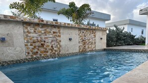 Una piscina con un muro in pietra e un edificio moderno sullo sfondo.