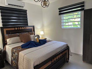 A neatly made bed with a headboard, a bedside lamp, and a window with blinds. - Villa Esmeralda-Peaceful 2-bedroom house with AC in charming Willemstad (Willemstad)