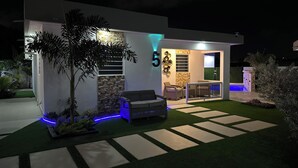 Una casa moderna con patio, area salotto esterna e piscina.