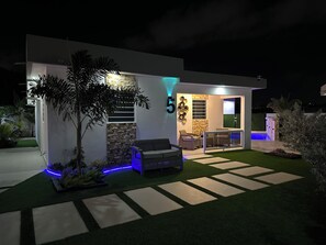 Ein modernes Haus mit Terrasse, Sitzgelegenheiten im Freien und einem Swimmingpool.