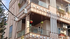 A multi-story building with balconies, a gated entrance, and potted plants.