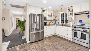 A modern kitchen with stainless steel appliances, white cabinetry, and a tiled floor. - Hot Tub-Creekside Yosemite Family Oasis - 5 min to Town-Foosball, Pets Welcome (Mariposa)