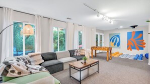 A modern living room with a sofa, coffee table, and a foosball table. - Hot Tub-Creekside Yosemite Family Oasis - 5 min to Town-Foosball, Pets Welcome (Mariposa)
