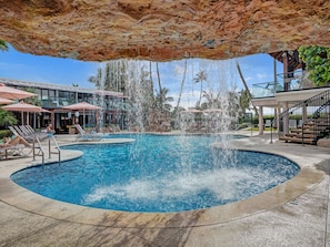 A pool area with a circular pool, lounge chairs, and a waterfall feature. - Modern 2BR 2BA Condo • Steps to Beach & Resort Amenities 1411 (Miami Beach)