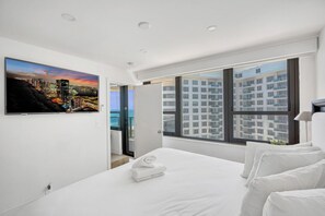 A modern hotel room with a large bed, a cityscape view, and a balcony. - Modern 2BR 2BA Condo • Steps to Beach & Resort Amenities 1411 (Miami Beach)