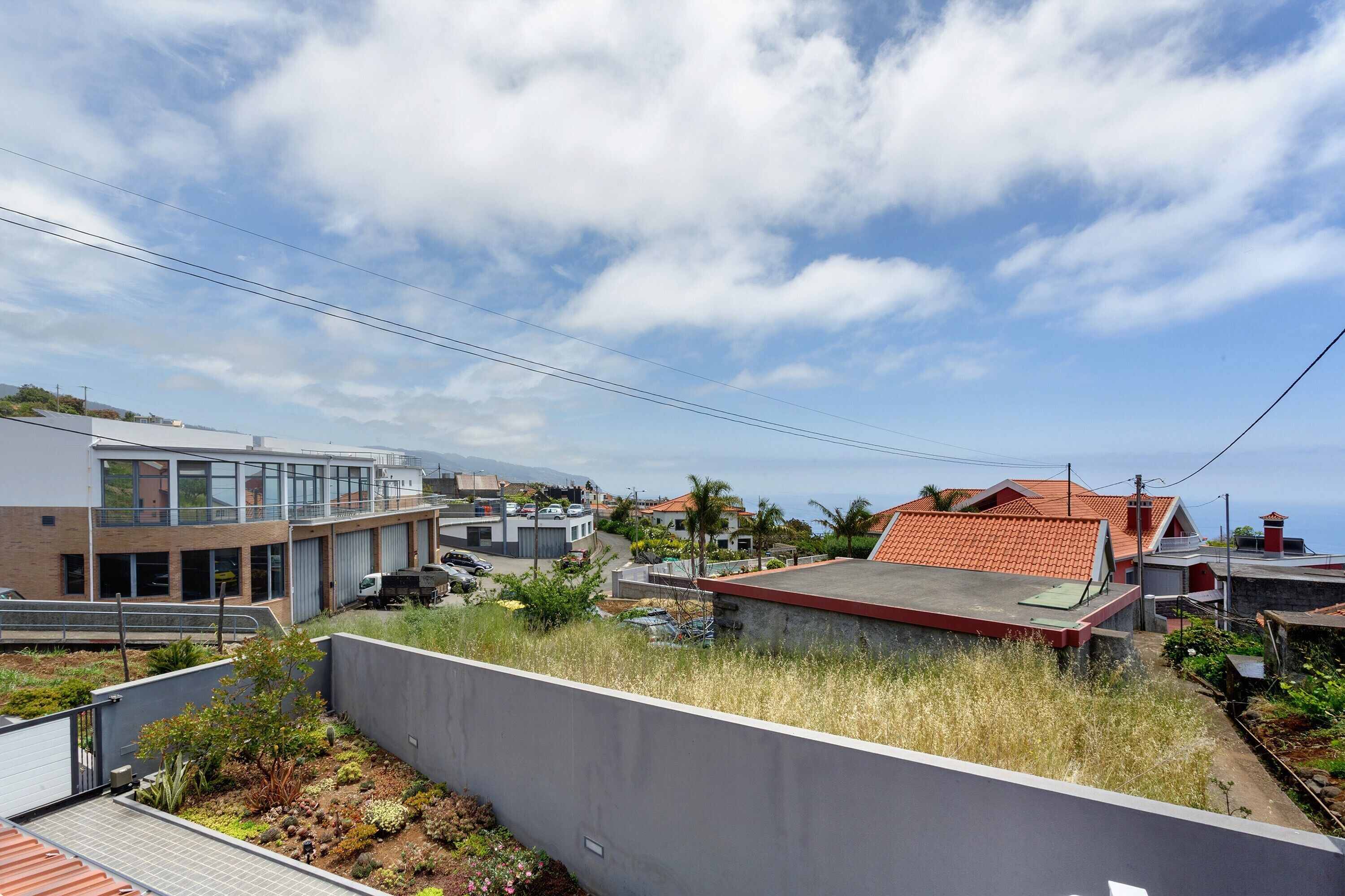A residential area with modern buildings, a rooftop garden, and a clear sky.