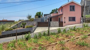 Ein modernes Haus mit Satteldach, einer Mauer aus Stein und einem gepflasterten Einfahrt.