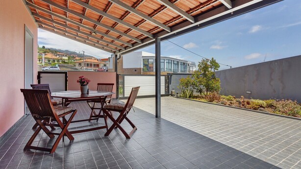 Eine Außenpatio mit überdachter Sitzgelegenheit, einem Tisch und Stühlen.