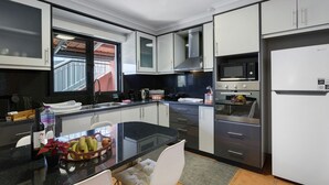 Eine moderne Küche mit schwarzem Arbeitsplatz, Edelstahlgeräten und einem Fenster, das für natürliches Licht sorgt.