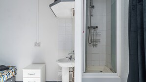 A bathroom with a shower, sink, and a bed with a storage unit. - Room 1 - The Archers (Southampton)