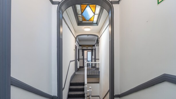 A narrow hallway with a staircase, a skylight, and a view into another room. - Room 1 - The Archers (Southampton)