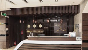 Un mostrador de recepción de diseño moderno, con un panel de pared de madera, varios relojes y lámparas colgantes.