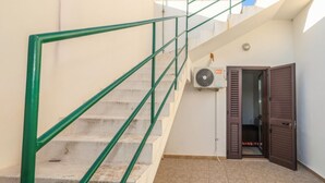 A staircase with green railings, a door, and an air conditioning unit mounted on the wall. - Clale House in Marina di Pescoluse (Marina di Pescoluse)