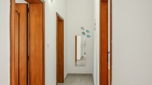 A hallway with wooden doors, a tiled floor, and a mirror reflecting fish decals on the wall. - Clale House in Marina di Pescoluse (Marina di Pescoluse)