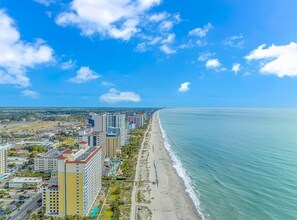 Eine Küstenstadt mit Hochhäusern, einem Strand und strahlend blauem Himmel.