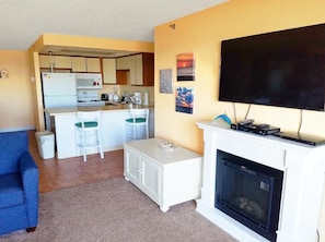 Ein Wohnzimmer mit Kamin, Fernseher und Küchenbereich mit Kühlschrank und Mikrowelle.