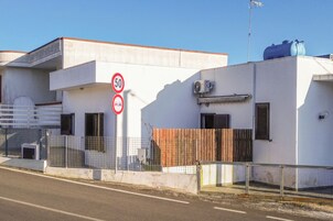 A building with a white facade, a speed limit sign, and a security camera.