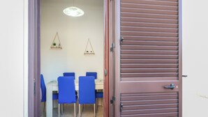 A dining area with a table and chairs, a door, and wall-mounted decorations. - Casa Clale (Marina di Pescoluse)