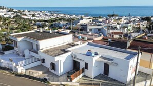 A residential area with white buildings, a road, and a view of the sea. - Casa Clale (Marina di Pescoluse)
