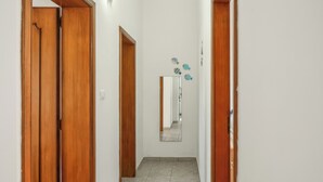 A hallway with wooden doors, a tiled floor, and a mirror reflecting the hallway. - Casa Clale (Marina di Pescoluse)