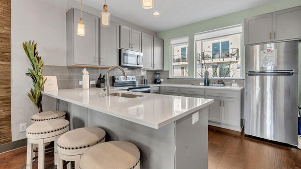 A modern kitchen with a large island, stainless steel appliances, and a view of a building outside. - The Urban Cowboy (Nashville)