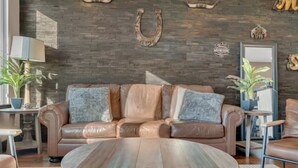 A leather sofa with pillows, a round coffee table, and a wall with a horseshoe decoration. - The Urban Cowboy (Nashville)