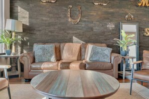 A leather sofa with pillows, a round coffee table, and a wall with a horseshoe decoration. - The Urban Cowboy (Nashville)