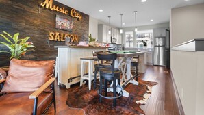 A modern kitchen with a bar area, wooden wall decor, and a leather chair. - The Urban Cowboy (Nashville)