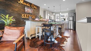 A modern kitchen with a bar area, wooden wall decor, and a leather chair. - The Urban Cowboy (Nashville)