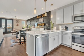 A modern kitchen with a central island, stainless steel appliances, and a city view. - The Urban Cowboy (Nashville)
