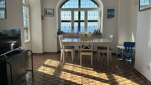Un espace repas doté d’une grande fenêtre en arc de cercle, d’un téléviseur et d’un sol à motifs.