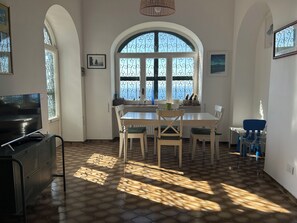 Ein Essbereich mit einem großen Bogenfenster, einem Fernseher und einem gemusterten Boden.