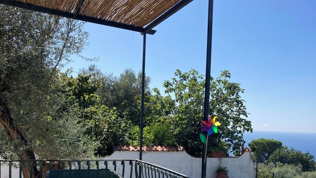 Une terrasse avec une table, des chaises, une lanterne et une vue sur la mer.