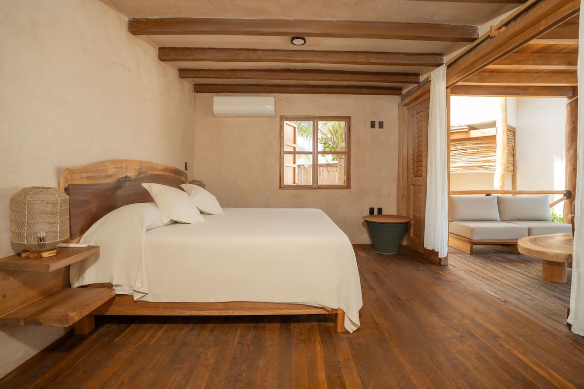 Un dormitorio con una cama de madera, una mesita de noche, una ventana y vistas a un espacio exterior.