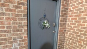 A grey door with a doormat and a small flower decoration. - Eclips 2-bedroom condo in Central Raleigh (Raleigh)
