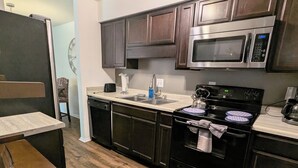 A modern kitchen with dark wooden cabinets, stainless steel appliances, and a wooden floor. - Eclips 2-bedroom condo in Central Raleigh (Raleigh)
