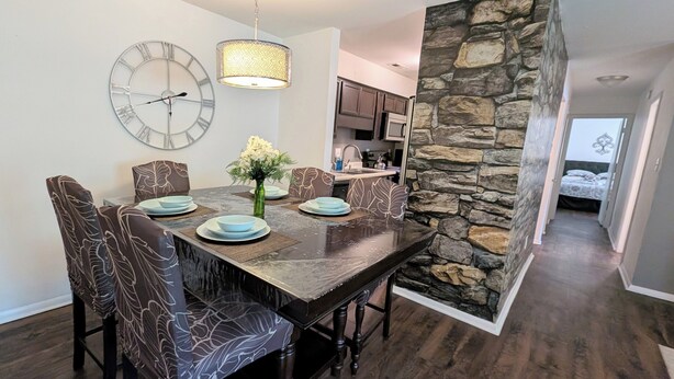 A dining area with a stone accent wall, a clock, and a modern chandelier. - Eclips 2-bedroom condo in Central Raleigh (Raleigh)