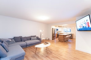 Ein modernes Wohnzimmer mit Sofa, Couchtisch und einer Küche im Hintergrund.