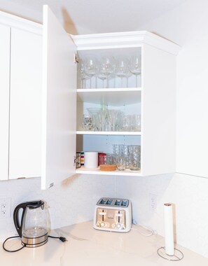 Eine Küche mit einem weißen Schrank, der Gläser, einen Toaster und einen Wasserkocher beherbergt.