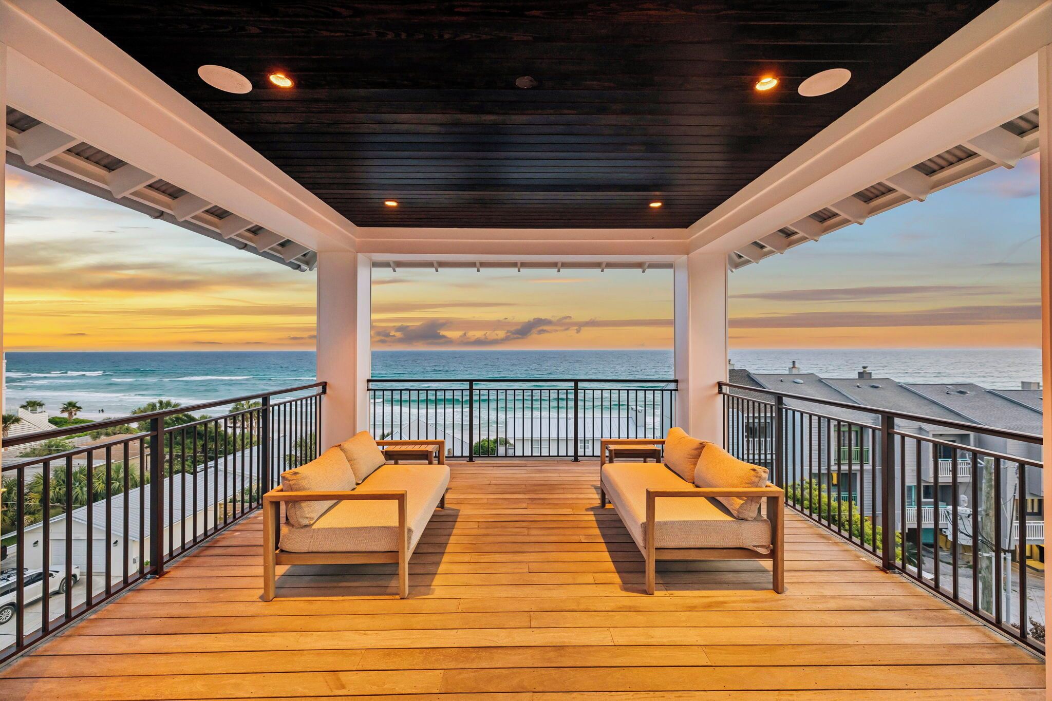 Ein Balkon mit zwei Sofas, der Blick geht auf einen Sonnenuntergang über dem Meer.