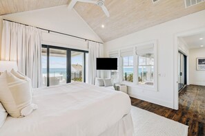 Ein Schlafzimmer mit einem großen Bett, einem Fernseher, einem Balkon mit Blick und einem Deckenventilator.