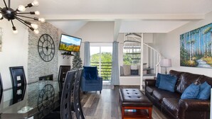 A modern living room with a fireplace, a television, a staircase, and a large window.
