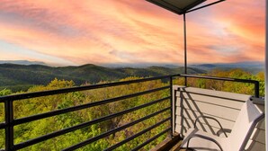 Un balcón con vista a un paisaje montañoso y una puesta de sol.