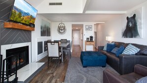 Una sala de estar moderna con chimenea, comedor, sofá y televisor montado en la pared.