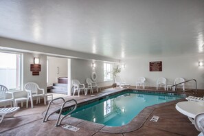 An indoor pool with clear water, surrounded by white chairs and a pool ladder. - Sleep Inn & Suites Idaho Falls Gateway To Yellowstone (Idaho Falls)