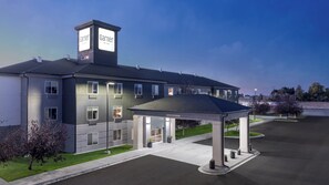 Ett modernt hotell med en inglasad entré, flera fönster och en skylt som anger att det är 13 fot högt till taket.