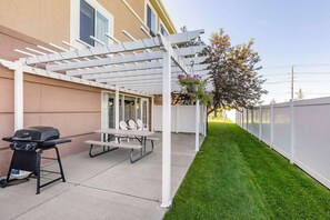 A patio with a grill, picnic table, and chairs, a white pergola, and a well-maintained lawn. - Sleep Inn & Suites Idaho Falls Gateway To Yellowstone (Idaho Falls)