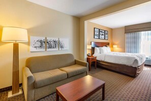 A hotel room with a sofa, a bed, a nightstand, a lamp, and framed artwork on the wall. - Sleep Inn & Suites Idaho Falls Gateway To Yellowstone (Idaho Falls)